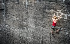 Woman using strength to climb up rocky cliffe